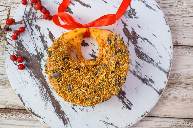 Tratta per gli uccelli selvatici in inverno Zucca fatta in casa alimenta semi di miglio di pancetta su un legno bianco