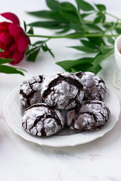 Tratta su un tavolo bianco Biscotti di crepe di cioccolato una tazza di tè e peonie