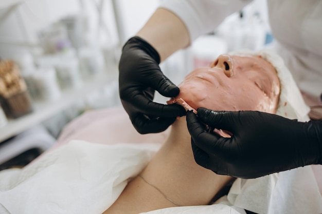 Trattamenti viso e corpo Il concetto di mantenimento della salute giovinezza e bellezza Maschere viso cosmetologia moderna estetista strumenti mani con guanti Tecniche di bellezza