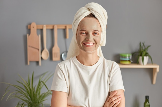 Trattamento per la cura della pelle Mattina rilassata Sorridente fiduciosa giovane donna in posa in cucina con asciugamano sulla testa mani incrociate godendo felice fine settimana e tempo libero