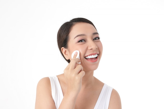 Trattamento per la pelle delle belle donne asiatiche, utilizzare una spugna per pulire il viso, la bellezza, attraente con un sorriso.