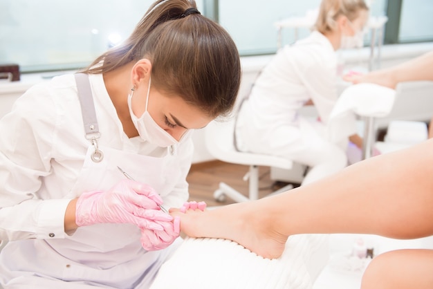 Trattamento piedi per due amici o sorelle nel salone SPA. Nail artist nel salone di bellezza che fa pedicure per i piedi dei clienti.