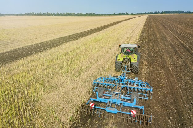 Trattore al lavoro, coltivando un campo, veduta aerea del coltivatore del letto di semina.