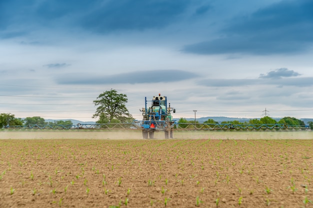 Trattore che spruzza sostanze chimiche sul campo per una migliore raccolta e controllo dei parassiti. copia spazio