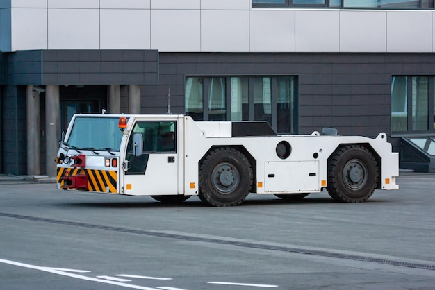 Trattore di traino dell'aeroplano presso il piazzale dell'aeroporto vicino al terminal