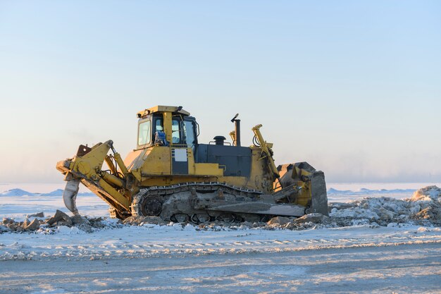 Trattore giallo nella tundra invernale. La costruzione della strada. Bulldozer.