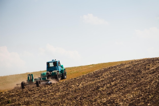 Trattore moderno in campo con complesso per l'aratura Il concetto di lavoro in un settore agricolo e dei campi