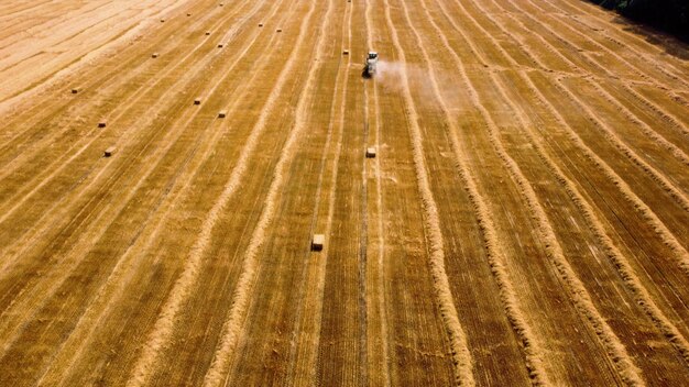 Trattore per balle di fieno trattore che raccoglie fieno in balle in campo in una giornata di sole vista aerea drone trattore d