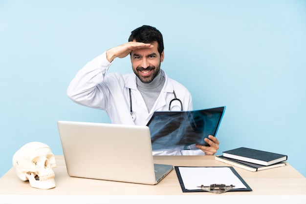 Traumatologo professionista sul posto di lavoro che guarda lontano con la mano per cercare qualcosa