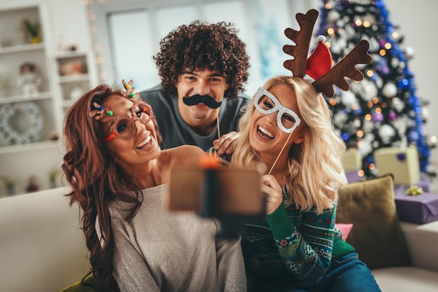 Tre allegri migliori amici si divertono in un appartamento e si fanno un selfie durante le vacanze di Natale.