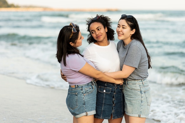 Tre amiche abbracciate sulla spiaggia