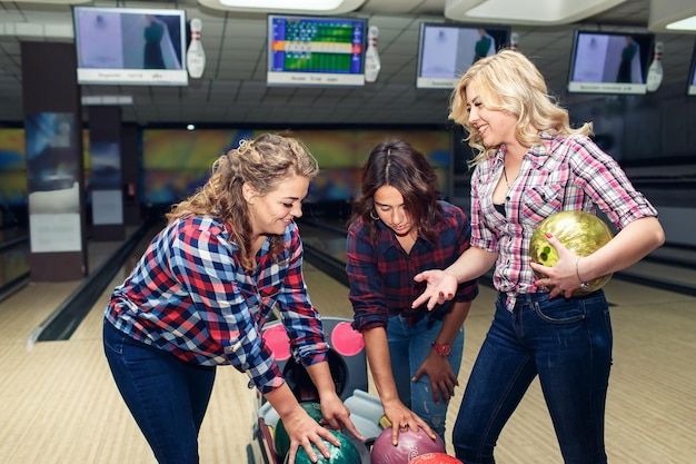 Tre amiche attraenti divertenti prendono le palle da bowling