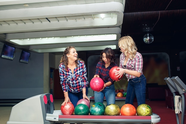 Tre amiche attraenti divertenti prendono le palle da bowling