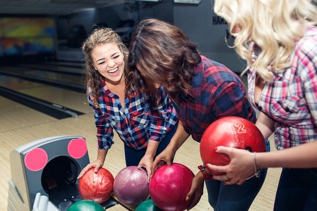 Tre amiche attraenti divertenti prendono le palle da bowling