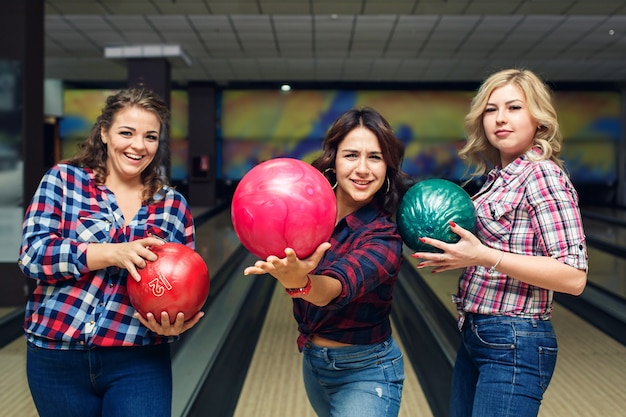 Tre amiche attraenti divertenti tengono le palle da bowling