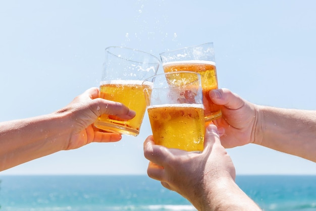 Tre amici che brindano con la birra su una spiaggia di fronte al mare Estate felice e divertente