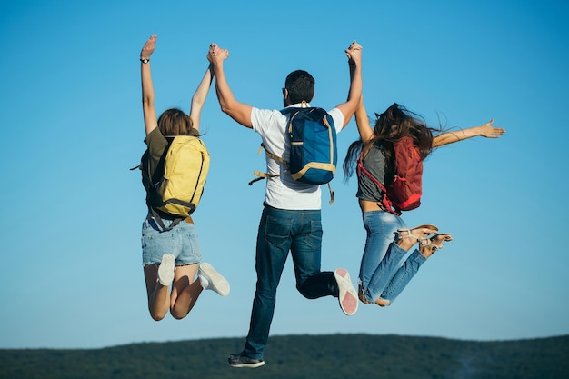 Tre amici che saltano sulla cima di una montagna sul cielo blu