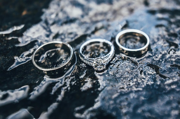Tre anelli di fidanzamento con diamanti fotografati su pietra bagnata natura sfondo astratto