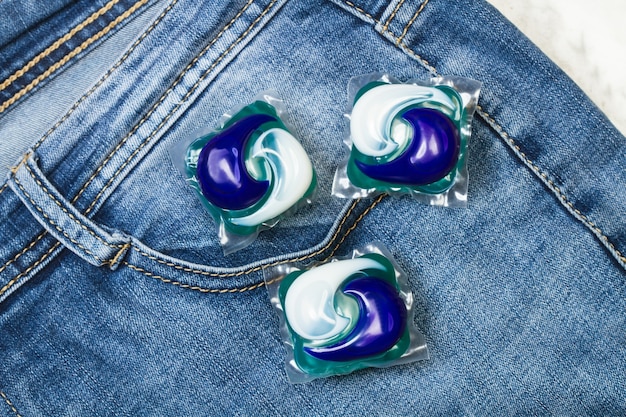 Tre baccelli del detersivo della lavatrice su un blue jeans in una vista dall'alto