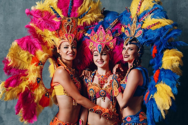 Tre ballerine in costume di carnevale di samba brasiliana con piumaggio di piume colorate