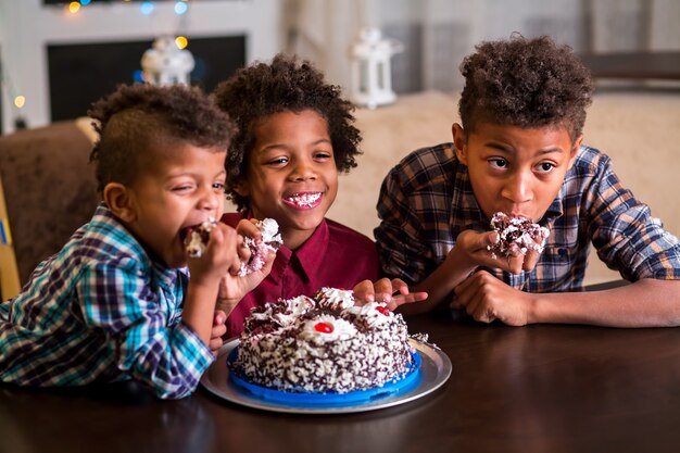 Tre bambini che mangiano una piccola torta.