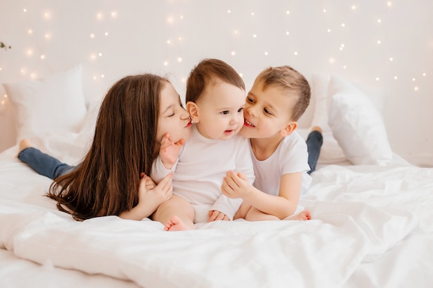 Tre bambini piccoli giacciono a letto e coccole, vista dall'alto. fratelli, famiglia numerosa