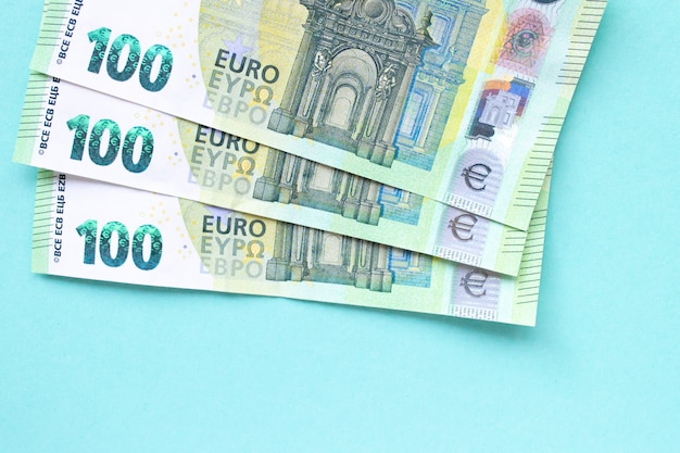 Tre banconote in tagli da 100 euro. Si trovano uno sopra l'altro sotto forma di un fan su sfondo blu. Concetto di denaro e finanza