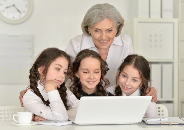 Tre belle bambine e una donna anziana che usano un laptop