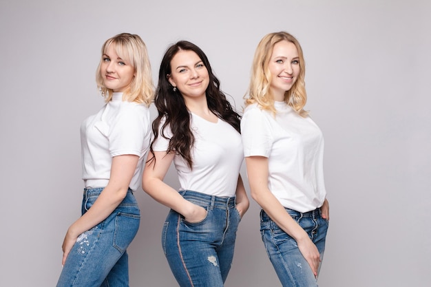 Tre belle donne in camicie bianche e jeans in posa