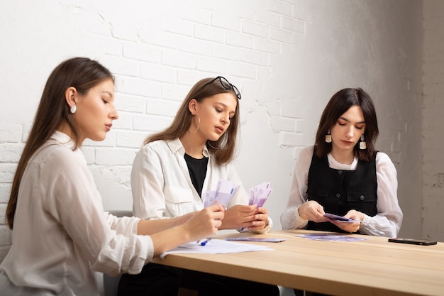 tre belle giovani donne al tavolo in ufficio con i soldi in euro