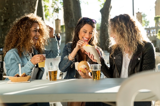 Tre belle giovani donne che visitano mangiare mercato in strada.