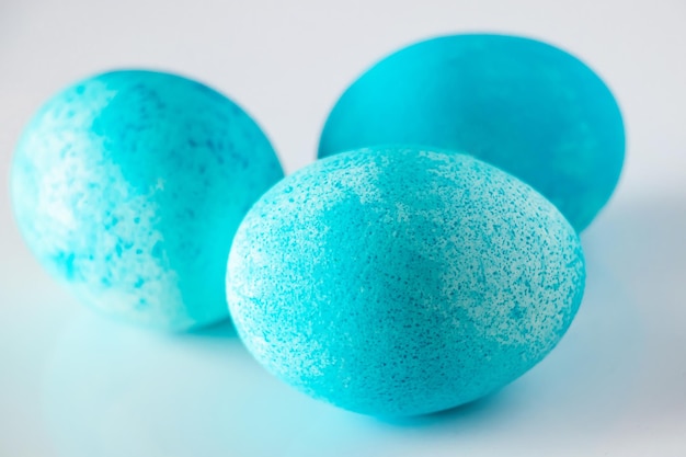 Tre belle uova di Pasqua dipinte blu primo piano su sfondo bianco