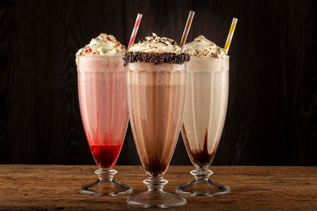 Tre bicchieri di milkshake con gusti assortiti. Frappè al cioccolato, vaniglia e fragola.