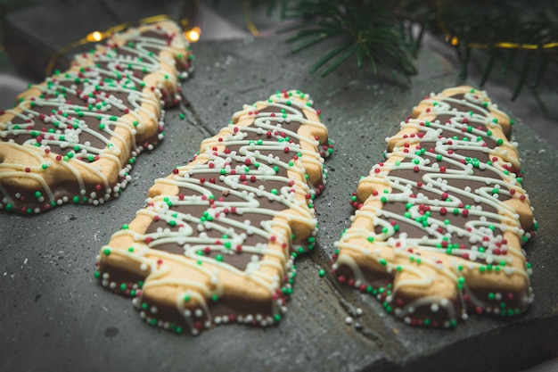 Tre biscotti a forma di albero di Natale con palline di cioccolato e confettini colorati