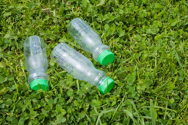 Tre bottiglie di plastica vuote giacciono sull'erba verde