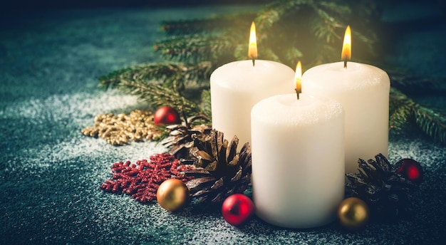 Tre candele di Natale accese e decorazioni su uno sfondo turchese scuro in formato banner