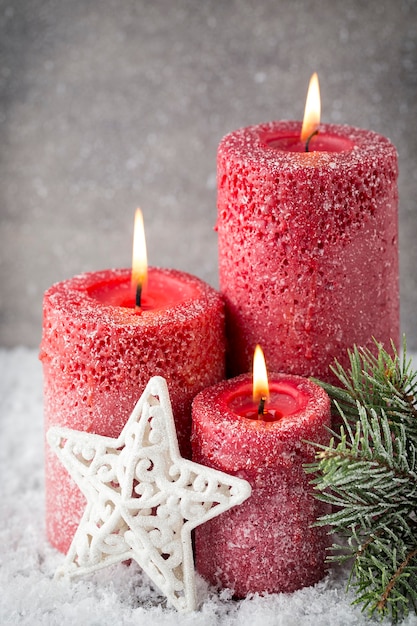 Tre candele rosse sulla superficie grigia, decorazioni natalizie. Atmosfera d'Avvento.