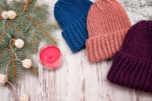 Tre cappelli. Blu, corallo e viola. Ramo di abete, ghirlanda e candela. Fondo in legno. Il concetto di Capodanno.