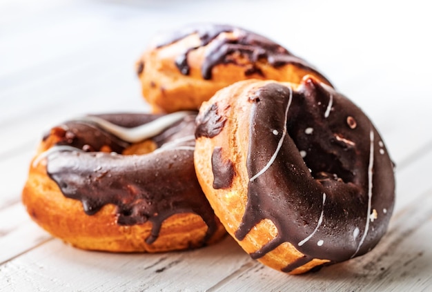 Tre ciambelle al cioccolato su un tavolo di legno bianco