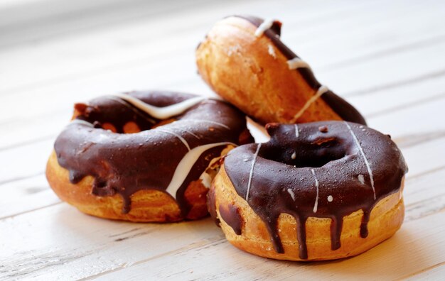 Tre ciambelle al cioccolato su un tavolo di legno bianco