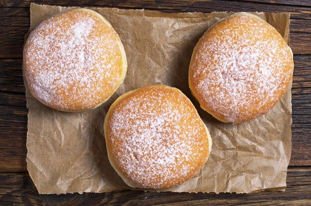 Tre ciambelle dolci su carta stropicciata sul tavolo, vista dall'alto