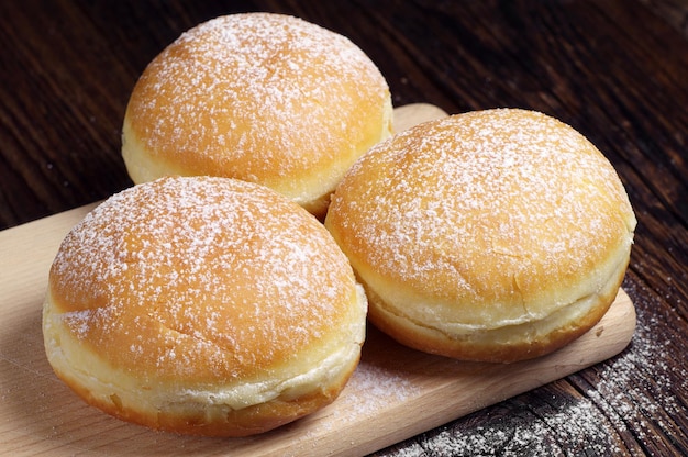 Tre ciambelle zuccherate su una tavola di legno