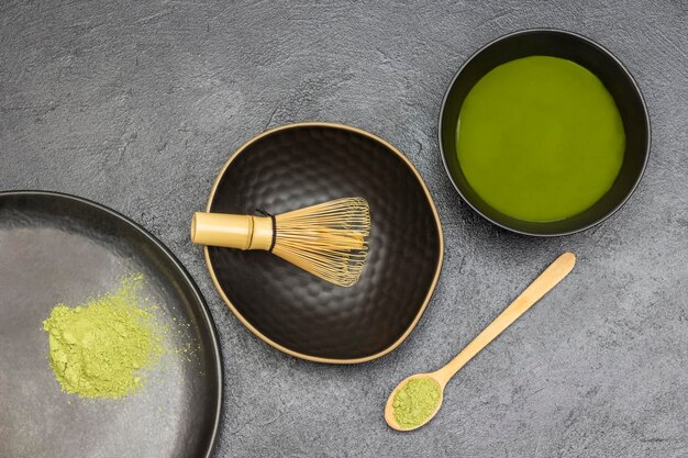 Tre ciotole nere con polvere di matcha verde e tè matcha Cucchiaio di legno con polvere di matcha