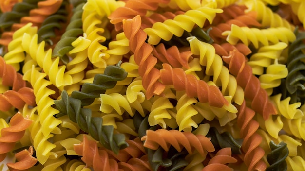 Tre colori Pasta di grano duro Pasta fusilli sfondo tricolore Texture astratta di pasta colorata modello di maccheroni Sfondo luminoso multicolor cibo Tagliatelle colorate crude