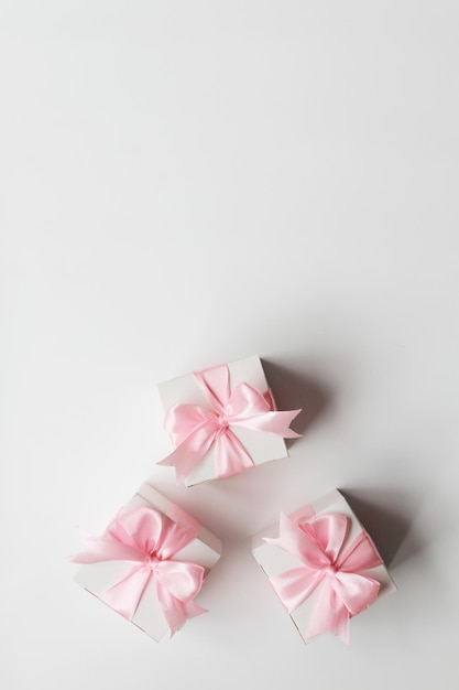Tre confezioni regalo con nastro di raso rosa isolato su sfondo bianco.