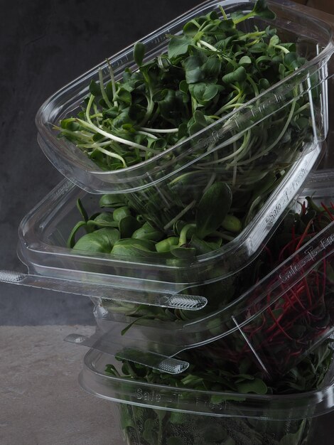 Tre contenitori di plastica di spinaci e spinaci sono impilati su un tavolo.