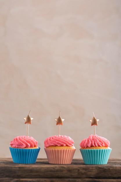 Tre cupcakes festivi decorati con panna e candele. Cupcake di compleanno. Muffin per feste. Copia spazio.