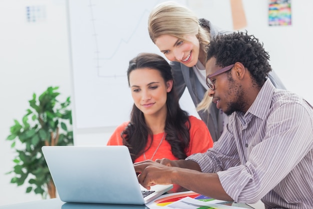 Tre designer che lavorano insieme su un laptop