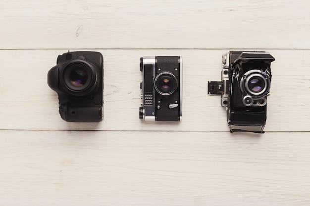 Tre diverse macchine fotografiche sul tavolo bianco, vista dall'alto. Confronto tra diverse generazioni di apparecchiature fotografiche. Concetto di progresso tecnologico, spazio di copia