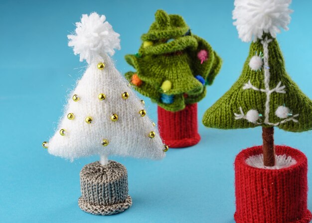 tre diversi alberi di Natale a maglia a mano su uno sfondo blu